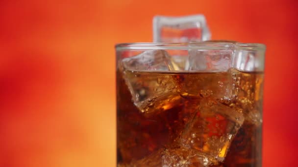 Cola med isbitar roterar närbild. Cola med is och bubblor i glas. Närbild av läsk. — Stockvideo