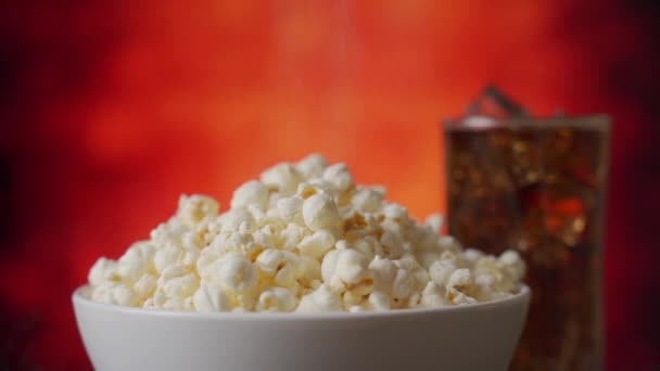 Hand saltning popcorn på bakgrunden av ett glas Cola — Stockvideo