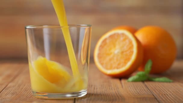 In Zeitlupe wird frischer Orangensaft in ein Glas geschüttet. — Stockvideo
