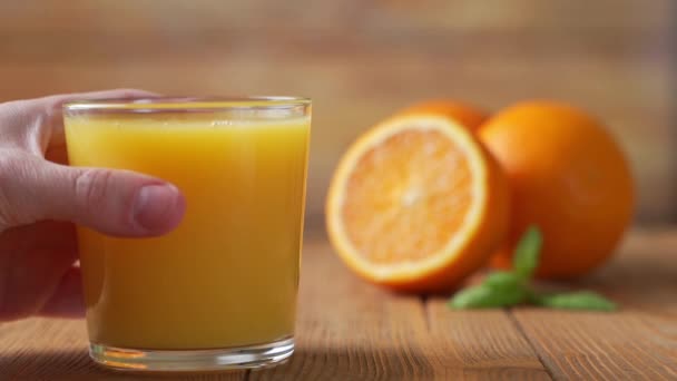 Mão pega um copo de suco de laranja espremido na hora — Vídeo de Stock