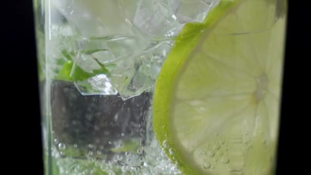 Erfrischendes Sodawasser aus nächster Nähe. Gießen Sie kohlensäurehaltiges Wasser in ein Glas Limette und Eis. Kalte Mojito-Limonade — Stockvideo