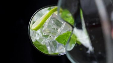 Yakın plan ferahlatıcı soda toniği. Bir bardak kireç ve buza karbonatlı su dök. Soğuk mojito limonatası.