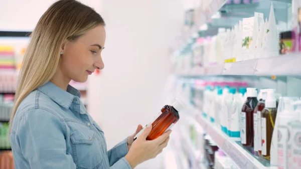 Zakupy - młoda kobieta trzymając butelkę szamponu w supermarkecie — Zdjęcie stockowe