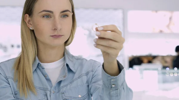 Una foto de una joven atractiva comprando joyas. Chica mirando a la mano tratando de elegir los anillos . — Foto de Stock