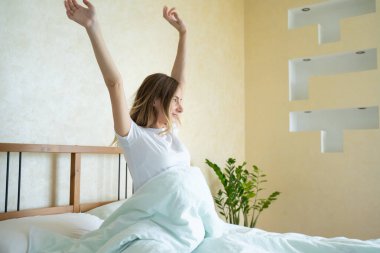 Yatağında dinlenmiş bir şekilde uyanan bir kadın. Uyandıktan sonra yatakta uzanan bir kadın..