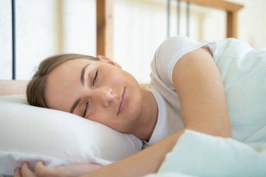 Kadın yatakta uyuyor ve sabahları dinleniyor.