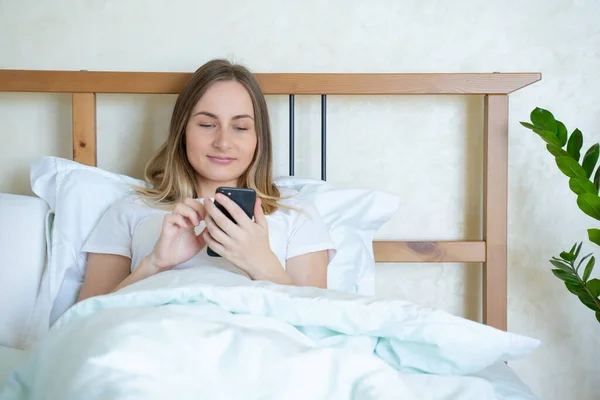 Mulher na cama verificando aplicativos sociais com smartphone — Fotografia de Stock