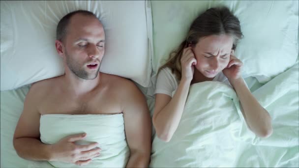 Недовольная расстроенная молодая женщина не может уснуть, пока ее парень храпит в постели в спальне. — стоковое видео