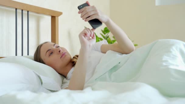 Frau im Bett checkt soziale Apps mit Smartphone — Stockvideo