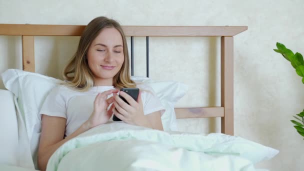 女人在床上检查社交应用程序与智能手机 — 图库视频影像