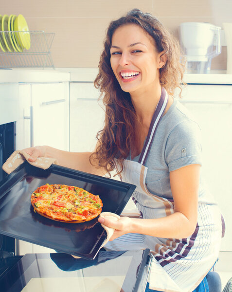 Happy young woman cooking pizza 