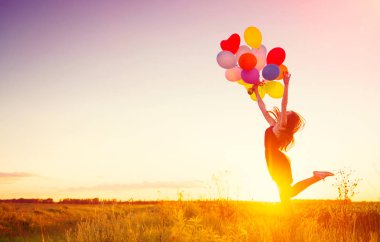 koşma ve atlama üzerinde günbatımı gökyüzü yaz alanda renkli hava balonları ile kız