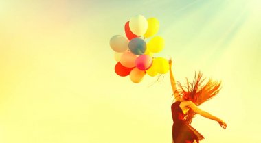koşma ve atlama üzerinde açık gökyüzü yaz alanda renkli hava balonları ile kız