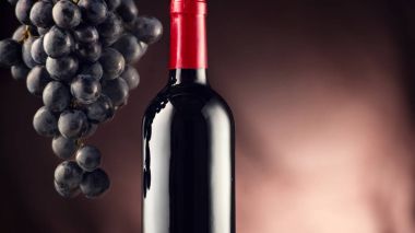 Siyah arka plan üzerinde olgunlaşmış üzümler ile kırmızı şarap şişe