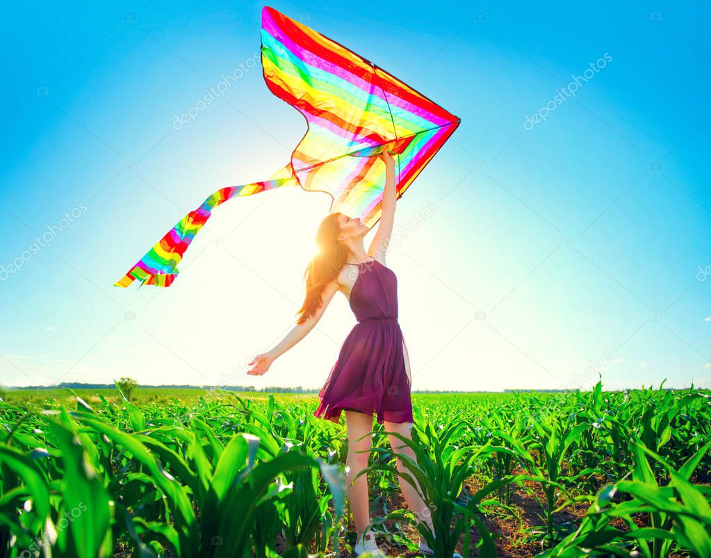 redhead girl with flying colorful kite over clear blue sky