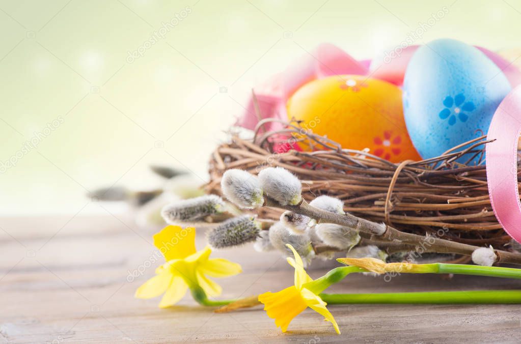 Easter colorful eggs in the nest with spring flowers