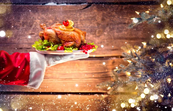 圣诞老人手捧烤火鸡在木制背景下的圣诞大餐 — 图库照片