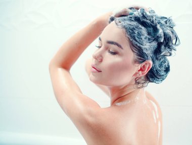 Duş almayı ve uzun siyah saçları yıkama genç kadın
