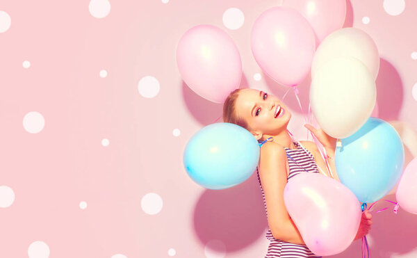 joyful teenage girl with colorful air balloons having fun over pink background with dots