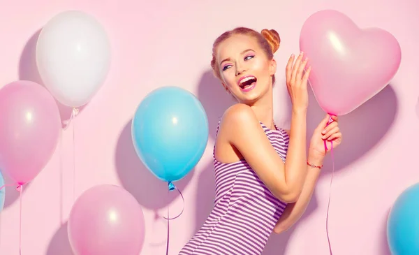 愉快的少女与五颜六色的空气气球有乐趣在粉红色背景 — 图库照片