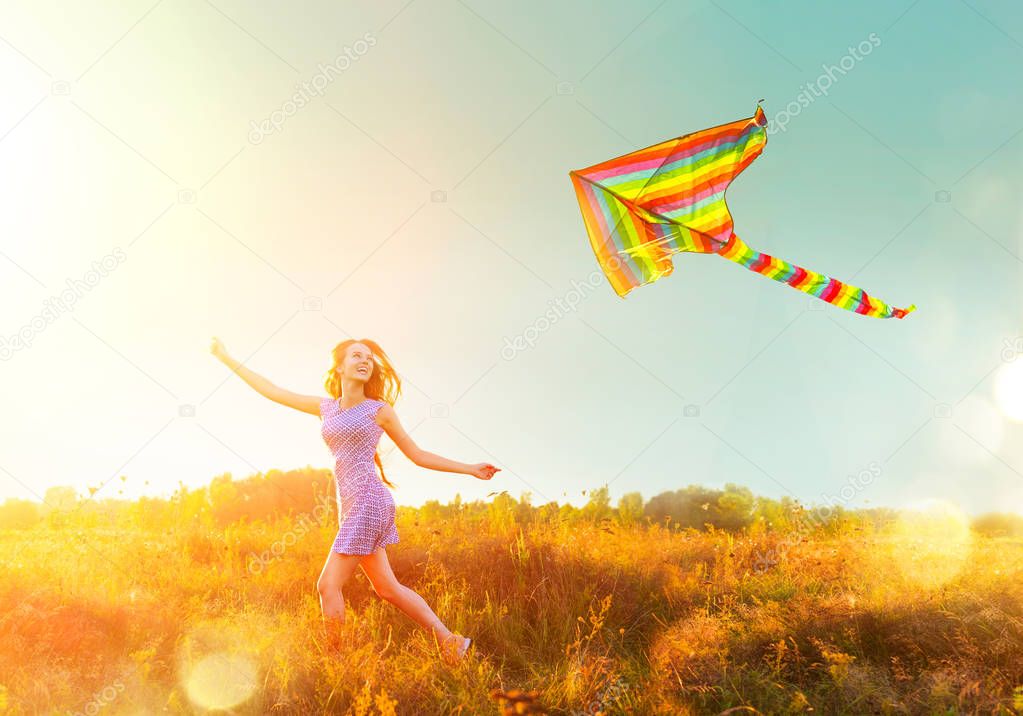 girl in short dress running with flying colorful kite 