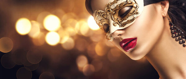 woman in golden masquerade carnival mask with bokeh on background