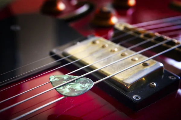 Guitarra acústica vermelha com plectro — Fotografia de Stock