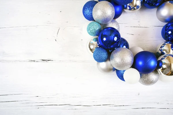 De kroon van Kerstmis van blauwe en witte ballen op houten witte oppervlak. — Stockfoto