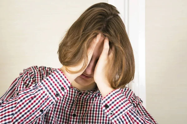 Guy with long hair hides the face in hands