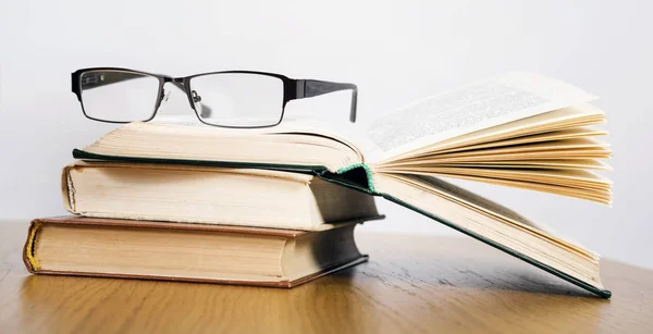 Açık kitap ve gözlük yığını — Stok fotoğraf