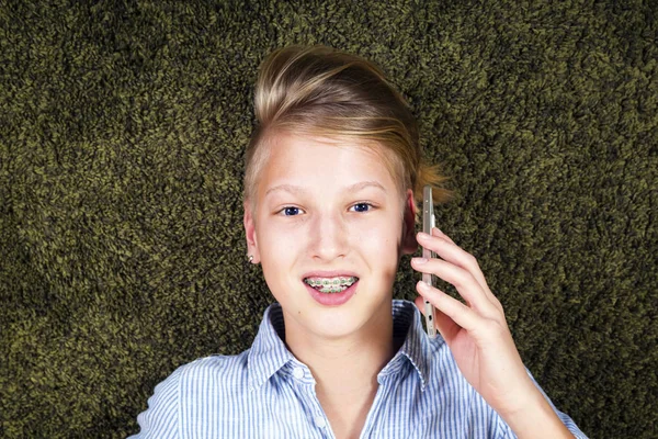 Adolescent avec téléphone.Avoir du plaisir adolescent se trouve sur un tapis . — Photo