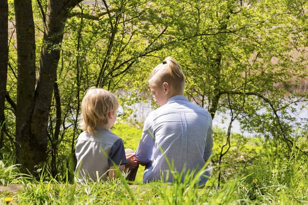 Två pojkar sitta på ett gräs i parken — Stockfoto