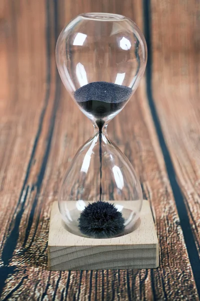 Hourglass, iron  sand on wooden background — Stock Photo, Image