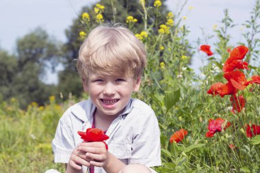 Elinde kırmızı bir haşhaş ile güzel sarışın çocuk.