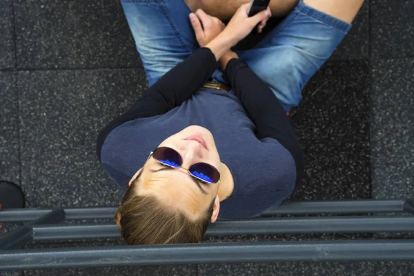 Хлопець сидить з сонцезахисними окулярами і телефоном — стокове фото