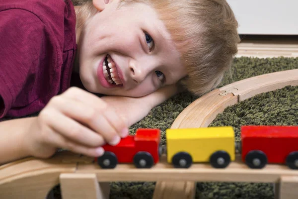 Child boy play with wooden train, build toy railroad at home or — Stock Photo, Image