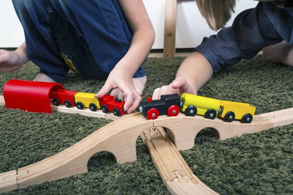 Hermanos juegan con tren de madera, construir ferrocarril de juguete en casa o d —  Fotos de Stock