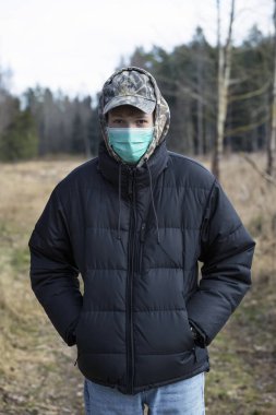 Yüzünde koruyucu steril tıbbi maske takmış bir çocuk dışarıdaki kameraya bakıyor. Hava kirliliği, virüs, Çin salgını koronavirüs konsepti. 