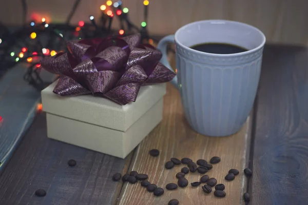 Белая подарочная коробка, голубая чашка, кофейная фасоль на столе — стоковое фото