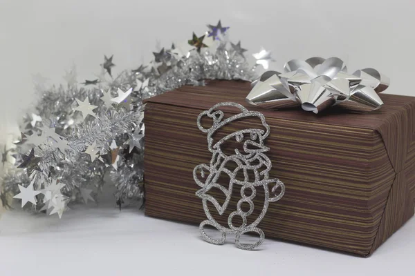 Braune Schachtel mit einem Geschenk und einem Schneemann auf hellem Hintergrund — Stockfoto