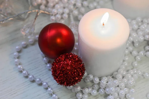 White candle, red christmas balls, perly white beads