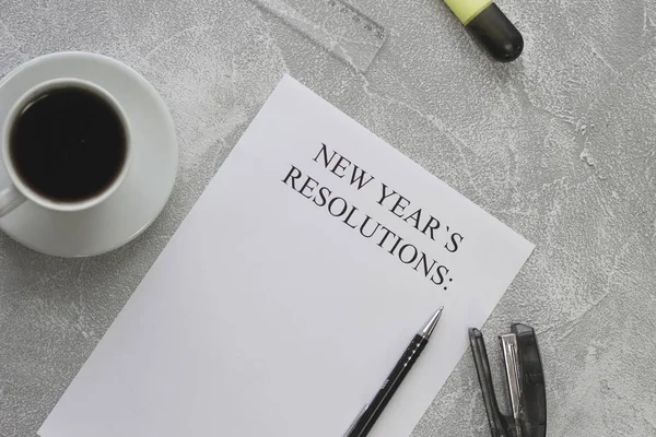 Uma xícara de café preto e um papel de resolução de Ano Novo com papelaria — Fotografia de Stock
