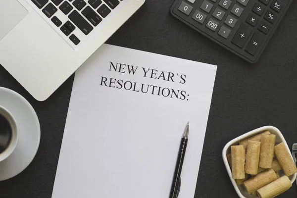 New Years resolutions paper, a bowl of cookies,coffee, laptop,office supplies — Stock Photo, Image