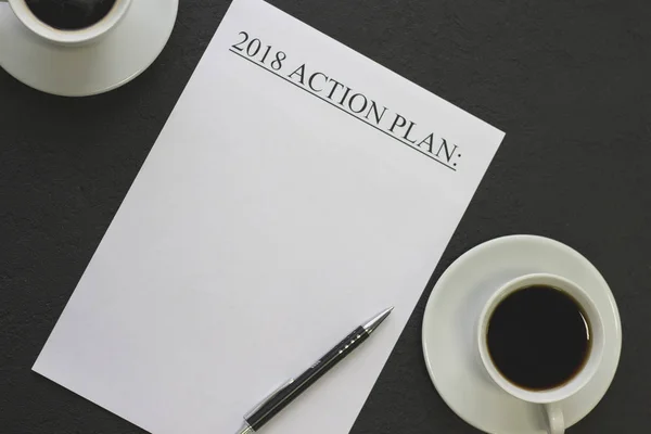 2018 action plan paper with white coffee cups and a black pen