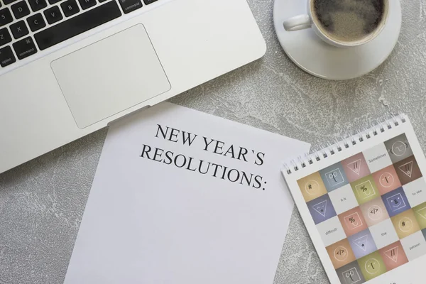 O papel de resoluções de Ano Novo, um caderno, um computador portátil, uma xícara de café — Fotografia de Stock