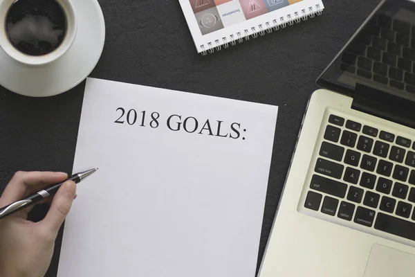 Hand writing 2018 goals, a coffee cup and a laptop — Stock Photo, Image