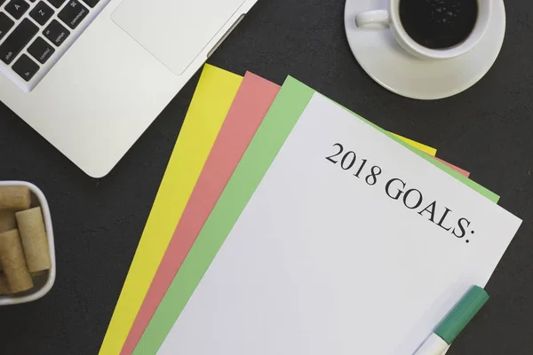 2018 goals paper on colored paper sheets, coffee, cookies,a green highlighter and a laptop — Stock Photo, Image