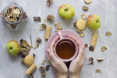 Bir çay bardağı, Cam Kavanoz, kuru çiçekler ve elma holding eller
