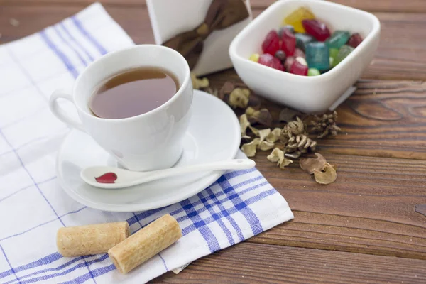 Still life with a tea cup,saucer, spoon,a bowl of candies and a gift box — Stock Photo, Image
