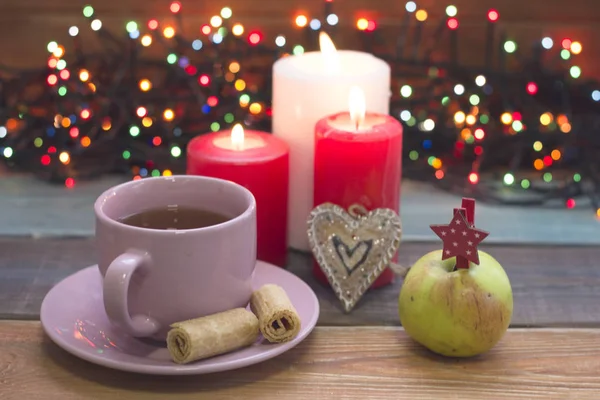 A festive still life with tea, burning candles, a gingerberad and an apple — Stock Photo, Image